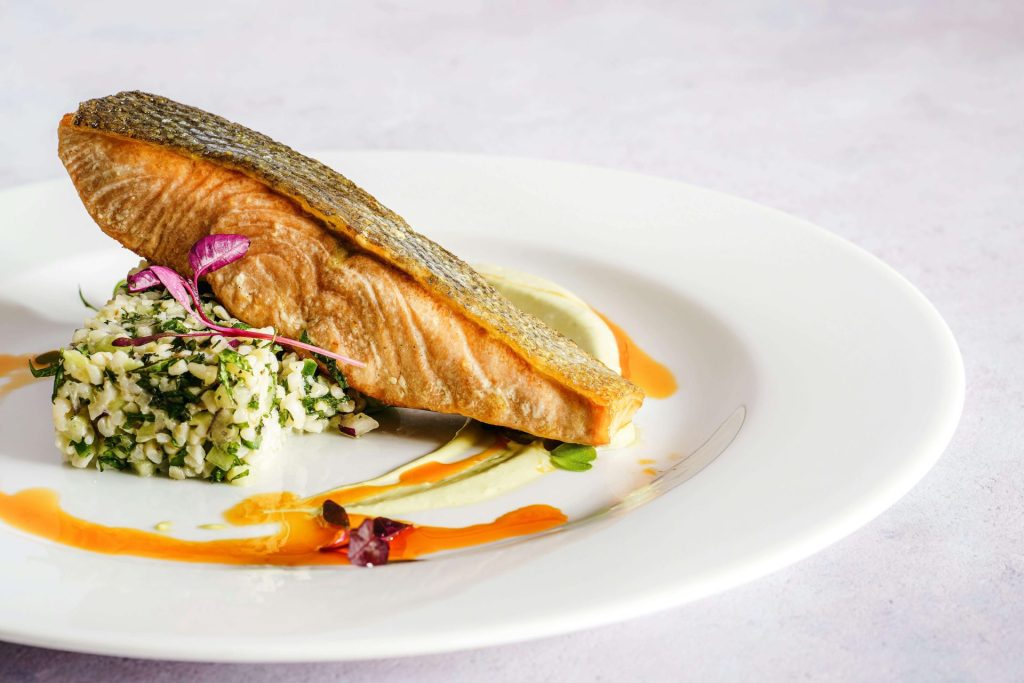 salmon filet on a plate with grains and sauce